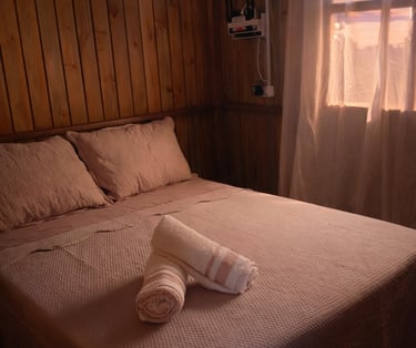 cama de casal da cabana, arrumada, confortável e com toalhas enroladas em cima