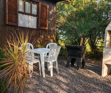 Área de lazer externa da cabana com churrasqueira, tanque e mesa.