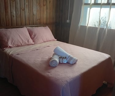 cama de casal da cabana, arrumada, confortável e com toalhas enroladas em cima