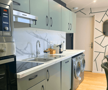 Cuisine équipée moderne avec électroménagers et plan de travail marbré dans maison meublée.