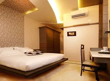 Modern hotel room with a smart TV, desk, and coffee table.