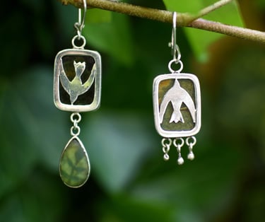 a pair of hand made earrings a bird and flower with seaglass
