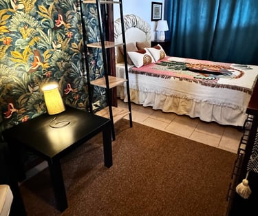 Cozy guest bedroom with tropical wallpaper and reading lamp in beachfront villa Siracusa, Sicily
