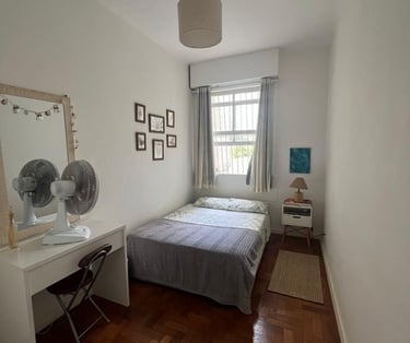 a bedroom with a bed and a desk with a fan