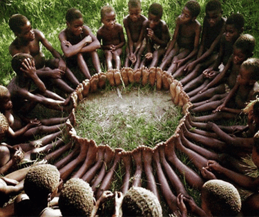 grupo de niños africanos con una escucha activasentados en el suelo creando un circulo con los pies 