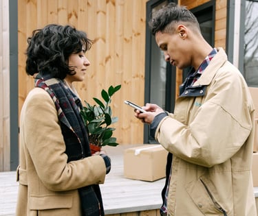 a man and woman standing outside a house using a mobile phone