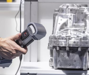 A technician using a portable handheld 3D scanner to digitally capture a complex metal cast engine c