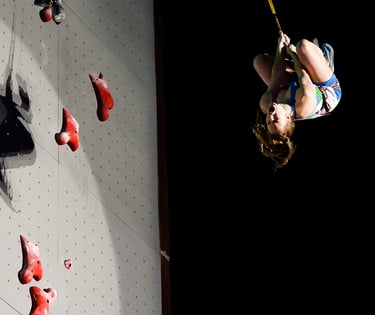 a woman is coming down from a speed climbing wall