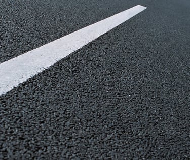 Close-up of a fresh black asphalt road surface with a single white painted traffic line.