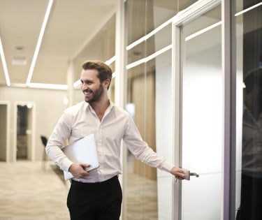A man in a white shirt and black pants entering conference room in a business