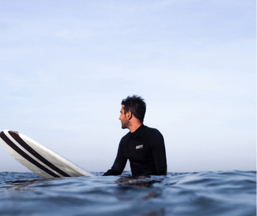 a man in a wetsuit is holding a surfboard