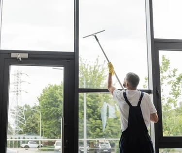 a man cleaning a window with a broom and a broom