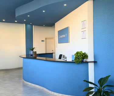 Recepción de la Clínica Bocarriba en El Médano, Tenerife sur, con un mostrador curvo azul