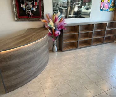 Modern wood reception desk and matching display shelving unit in a barber shop interior.