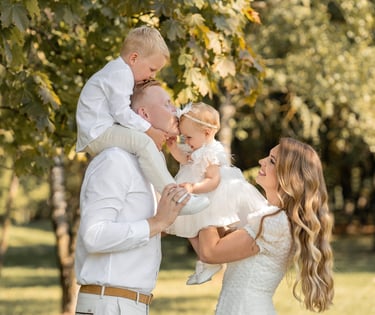 a man and woman holding a baby in a park