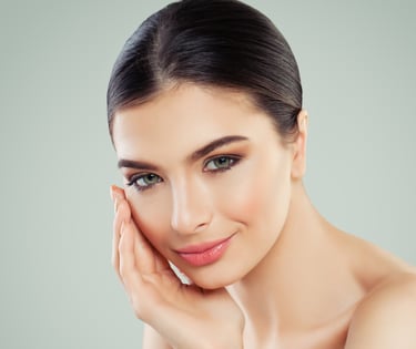 woman with green eyes and clear skin smiling with hand on cheek
