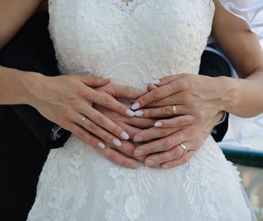 Close-up of bride and groom holding hands over the bride’s wedding dress during a wedding photoshoot