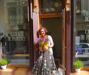a woman in a dress holding flowers in a vase standing in front of a store