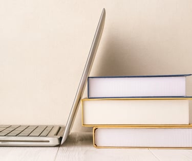 A laptop leaning against some books