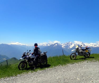 two people on a mountain top with mountains in the background