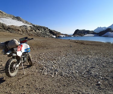 a motorcycle parked on a rocky beach next to a body of water