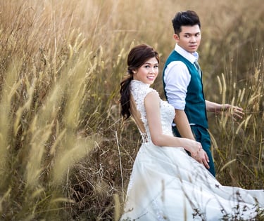 A man and woman standing in tall grass in wedding dress and suit