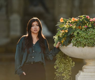 Une très belle femme pose devant une grande vasque fleurie, le soleil dans les cheveux