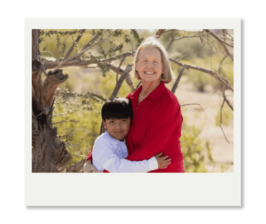 Smiling grandmother and grandson hugging outdoors in a sunny park landscape.