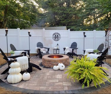 a patio with a fire pit and chairs
