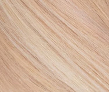 Close-up texture of silky strawberry blonde hair extensions with natural highlights.