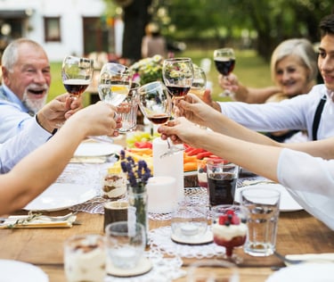 Multi-generational family toasting with wine glasses at a festive outdoor garden dinner party.