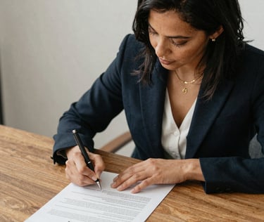 A professional notary in a blue shirt carefully reviewing documents at a client's home office.