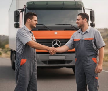 Two logistics workers in gray uniforms shaking hands in front of a large commercial truck.