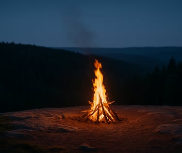 Large survival campfire burning on rocky outcrop with forest view at dusk