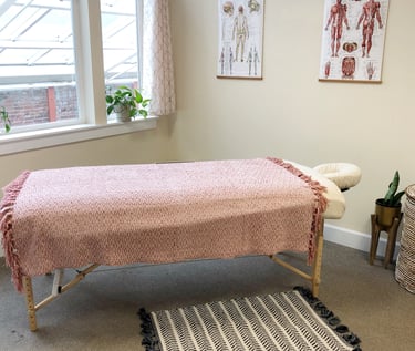Office interior with massage table and posters of human anatomy and nervous system.