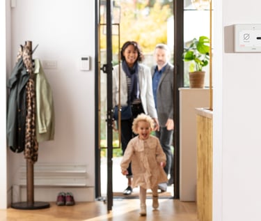 Family coming home with security panel on wall