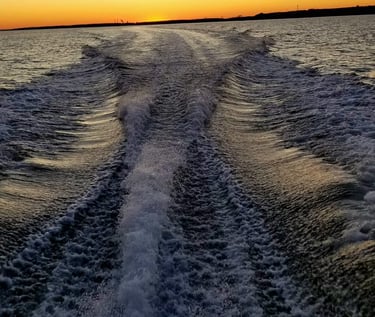 Pretty boat wake beneath a colorful sunset.