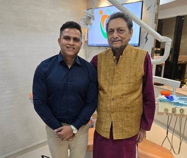 A male dentist in a blue shirt standing with a senior patient in a modern dental clinic.
