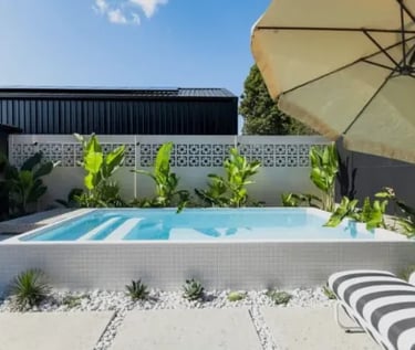 Modern raised plunge pool with pale blue water, white mosaic tiling and clean rectangular design