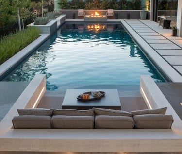 Contemporary geometric pool with calm blue-green water, light concrete coping and pale stone tiling.