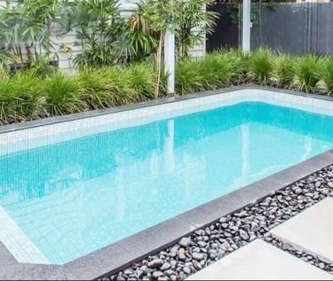 Sleek rectangular pool with light aqua water, fine white mosaic tiles and dark stone coping