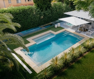 Geometric Rectangular pool with soft aqua water and beige coping tiles framed by lush green hedges