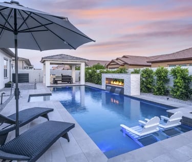 Modern Geometric rectangular pool with dark blue water and light stone tiles beside a fire feature
