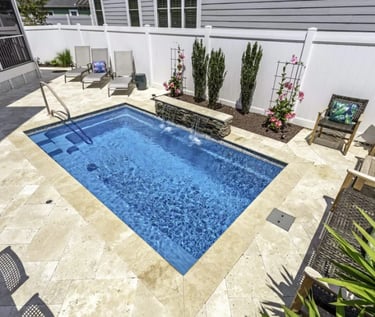 Rectangular plunge pool with clear blue water and light beige stone tiles in a classic courtyard des