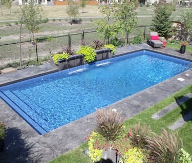 Contemporary rectangular pool with step entry, bright blue water and dark grey tiled surround.