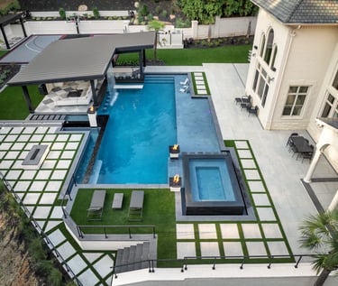 Modern geometric pool with deep blue water and light grey tile surrounds.