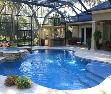 Curved resort-style pool with bright blue water and smooth blue interior, finished with pale stone p