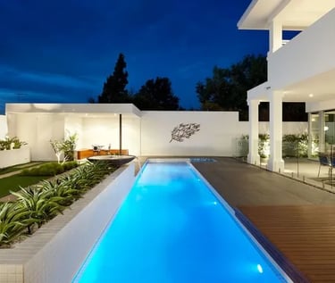 Long lap pool with clean rectangular design, glowing blue water and light mosaic tile interior.