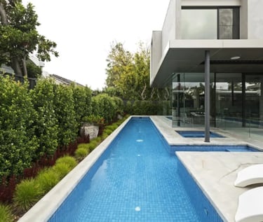 Narrow modern lap pool, clear blue water with fine light-blue mosaic tiling and concrete coping.