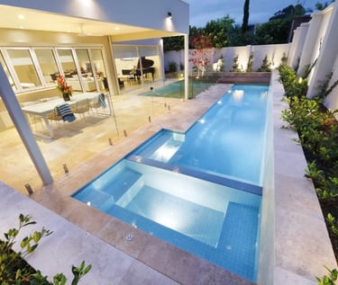 Slim contemporary lap pool, pale blue water, light blue mosaic tiles and beige stone coping